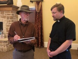 Fr. Kurtis Wiedenfeld and reporter at Centennial Tea